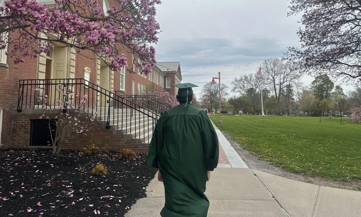 SUNY Brockport graduate Kurtis Walker walks acorss campus in his cap and gown as commencement approaches. (Jaden Ercolino/Canalside Chronicles)